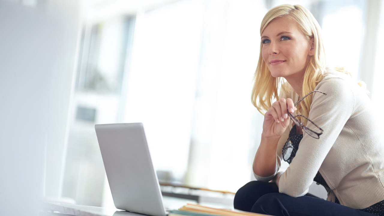 Professional woman thinking beside laptop during career planning