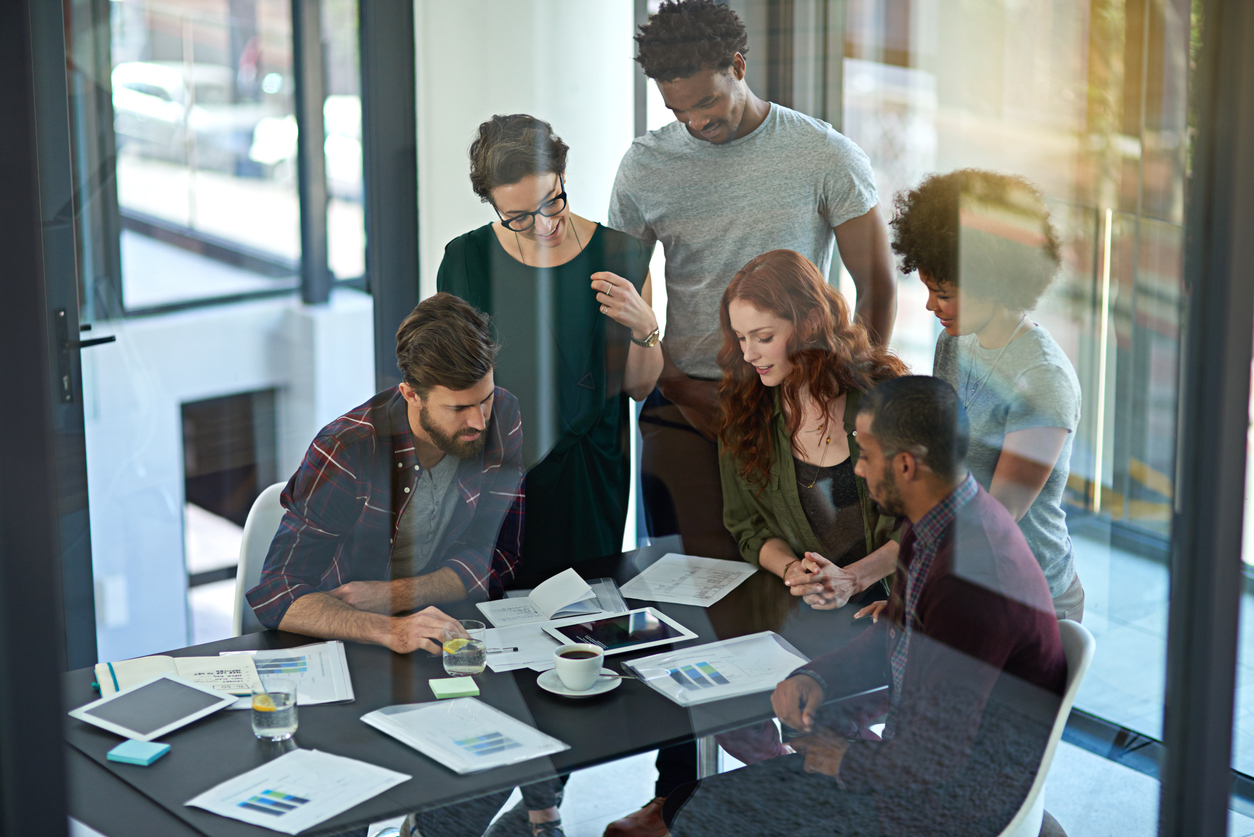 Cropped shot of a group of creatives working together on a digital tablet in a modern office
